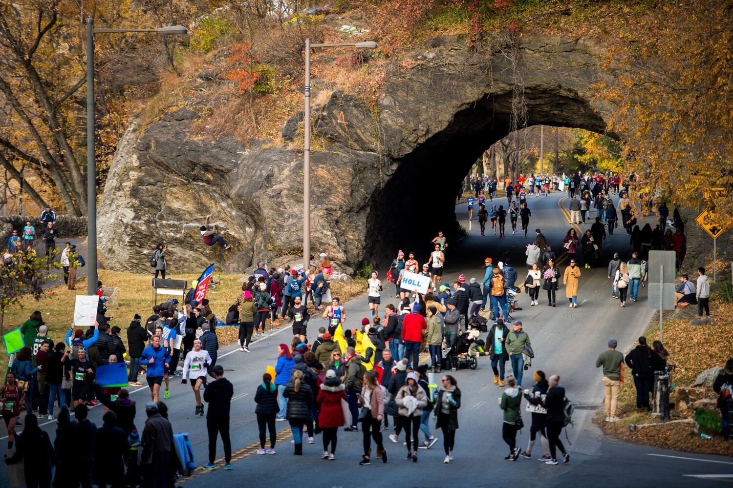 Runners running on a street, there is an old train tunnel bridge behind them in route